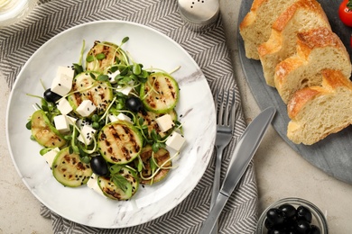 Photo of Delicious salad with grilled zucchini slices, feta cheese and olives on light grey table, flat lay