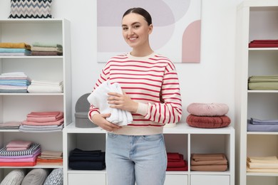 Photo of Smiling young woman holding new towels in home textiles store