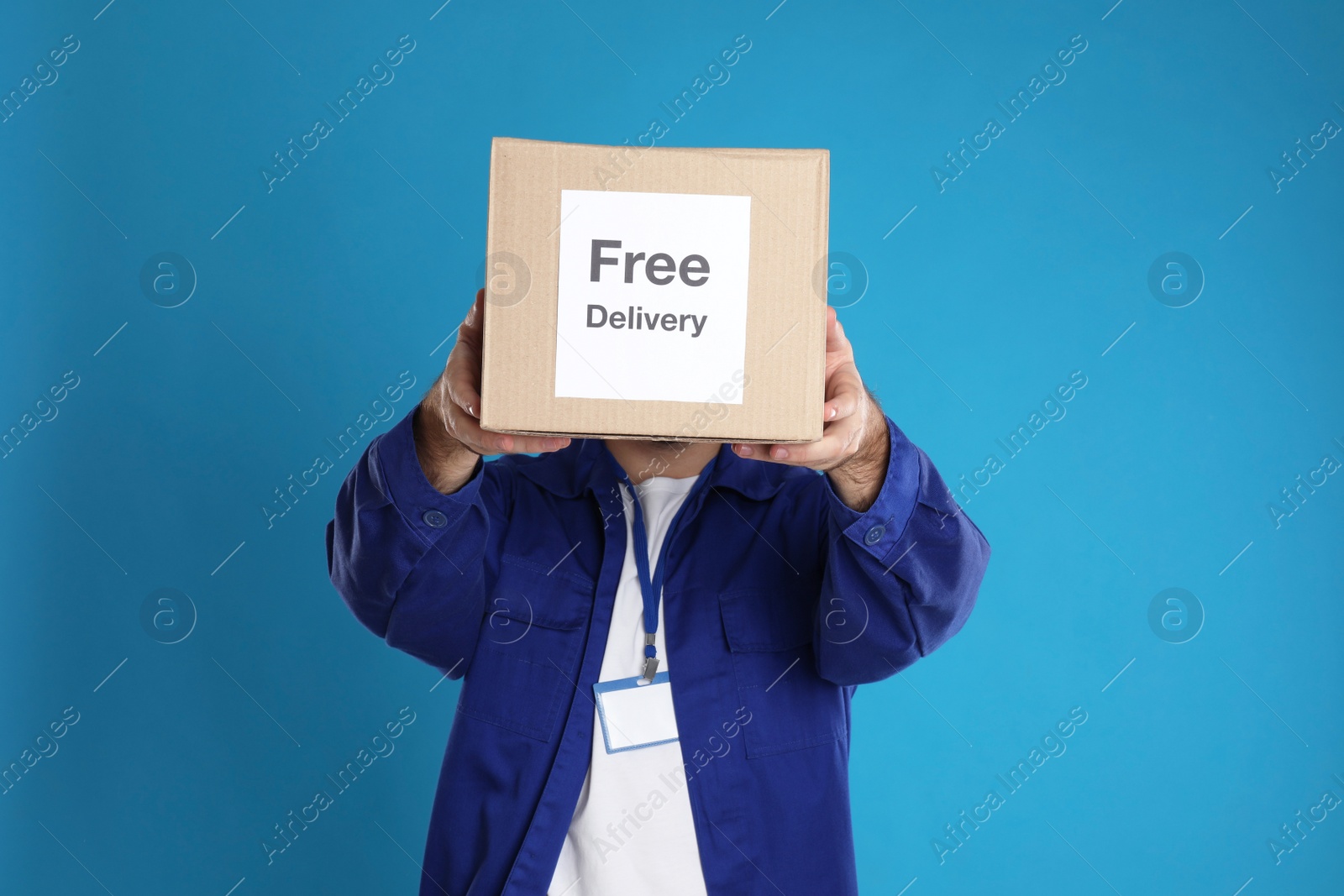 Photo of Male courier holding parcel with sticker Free Delivery on light blue background