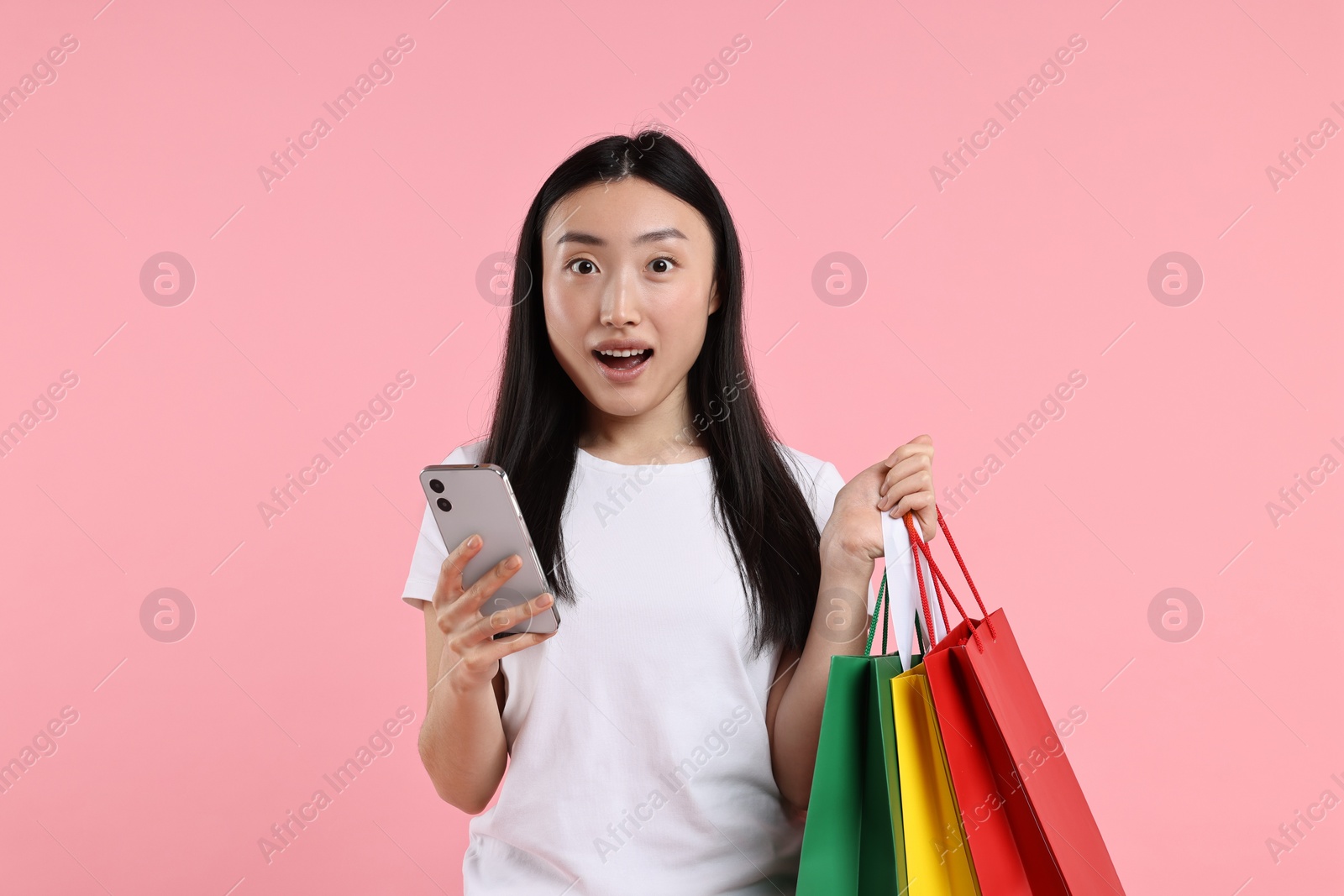 Photo of Surprised woman with shopping bags on pink background