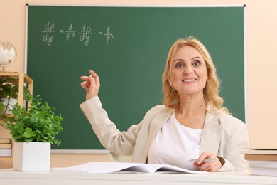 Photo of Professor pointing at green board with math equation in classroom