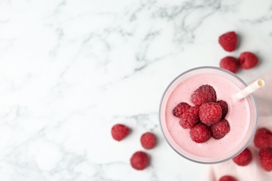 Image of Yummy raspberry smoothie in glass on white marble table, flat lay. Space for text 