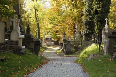 Photo of View of cemetery with granite tombstones and paved footpath on sunny day. Funeral ceremony