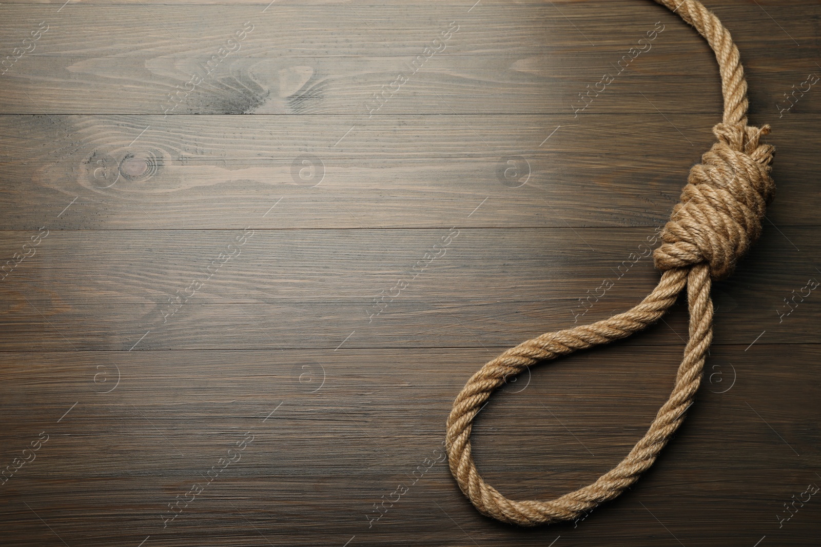 Photo of Rope noose on wooden table, top view. Space for text