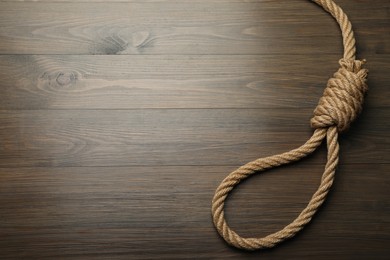 Photo of Rope noose on wooden table, top view. Space for text