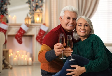 Happy mature couple with glasses of champagne at home. Christmas celebration