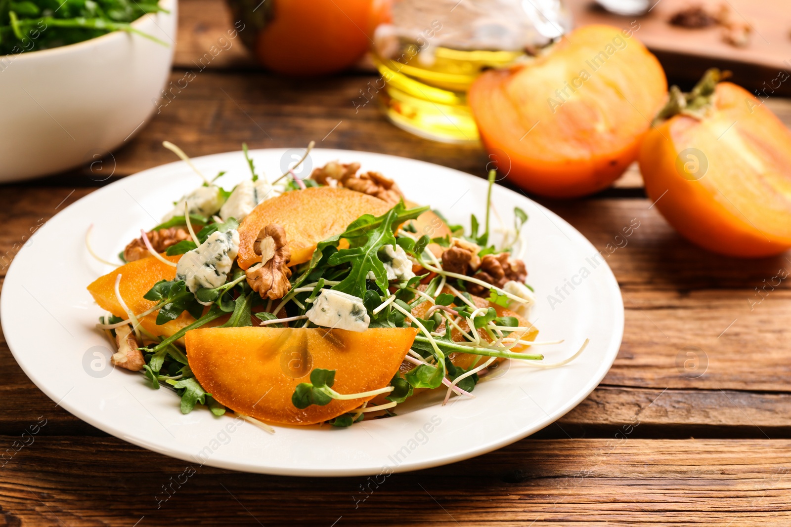 Photo of Delicious persimmon salad served on wooden table, closeup