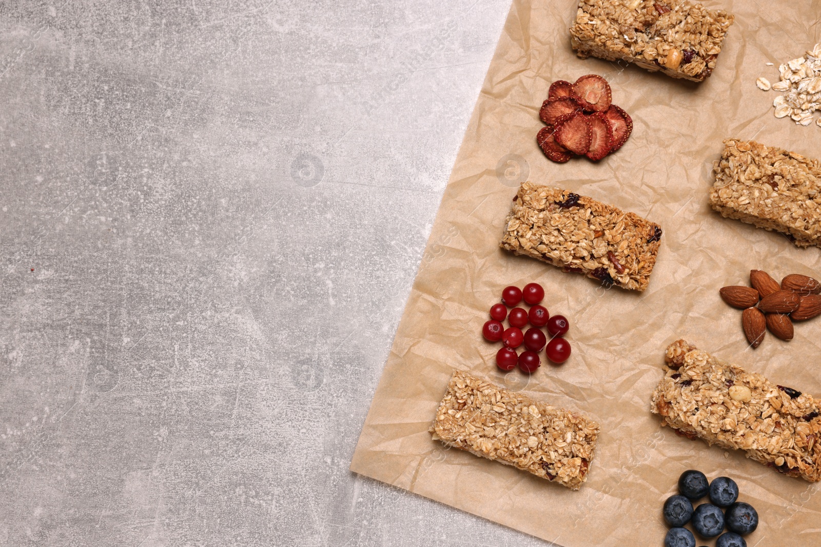Photo of Different tasty granola bars and ingredients on light grey background, flat lay. Space for text