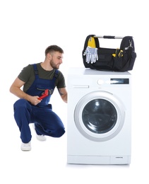 Plumber fixing washing machine on white background