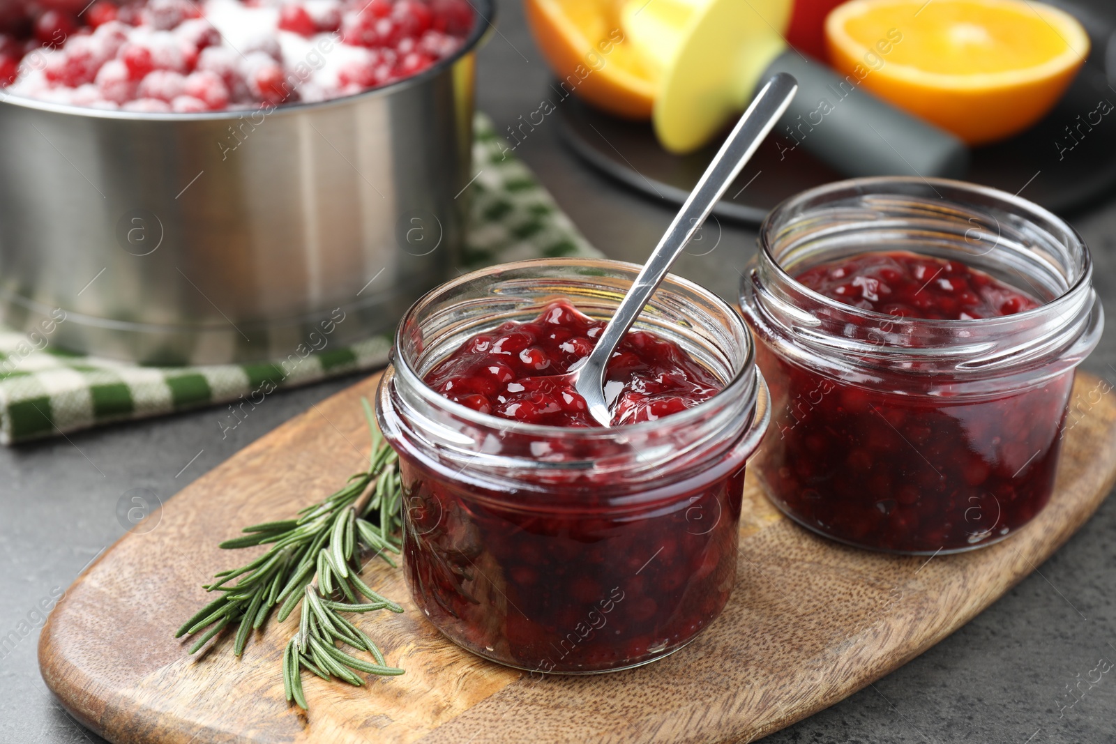 Photo of Fresh cranberry sauce in glass jars served on gray table, closeup