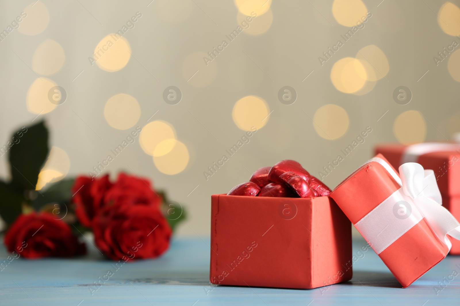 Photo of Heart shaped chocolate candies in gift box on light blue table. Valentine's day celebration