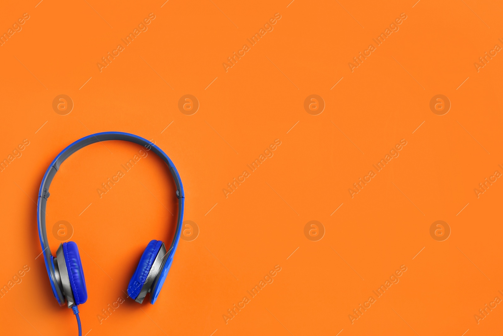 Photo of Stylish headphones on color background, top view. Space for text