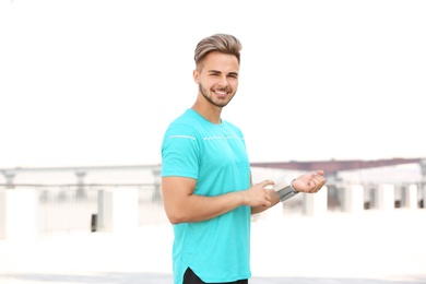 Young man checking pulse outdoors on sunny day