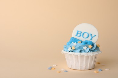 Photo of Delicious cupcake with light blue cream and Boy topper on beige background, space for text. Baby shower party