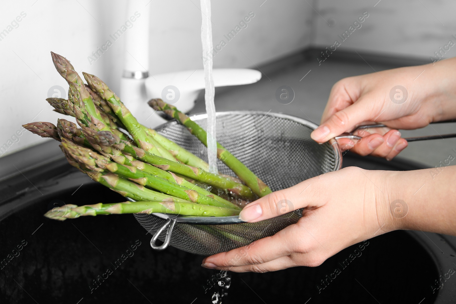 Photo of Woman washing fresh raw asparagus over sink, closeup