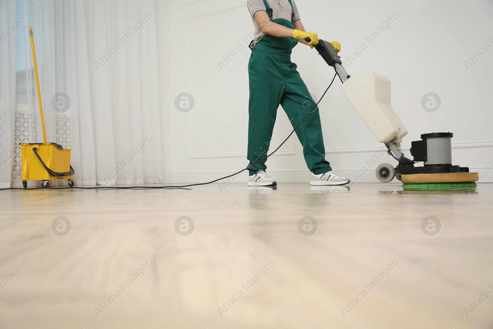 Photo of Professional janitor cleaning parquet floor with polishing machine indoors, closeup. Space for text