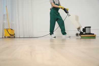 Photo of Professional janitor cleaning parquet floor with polishing machine indoors, closeup. Space for text