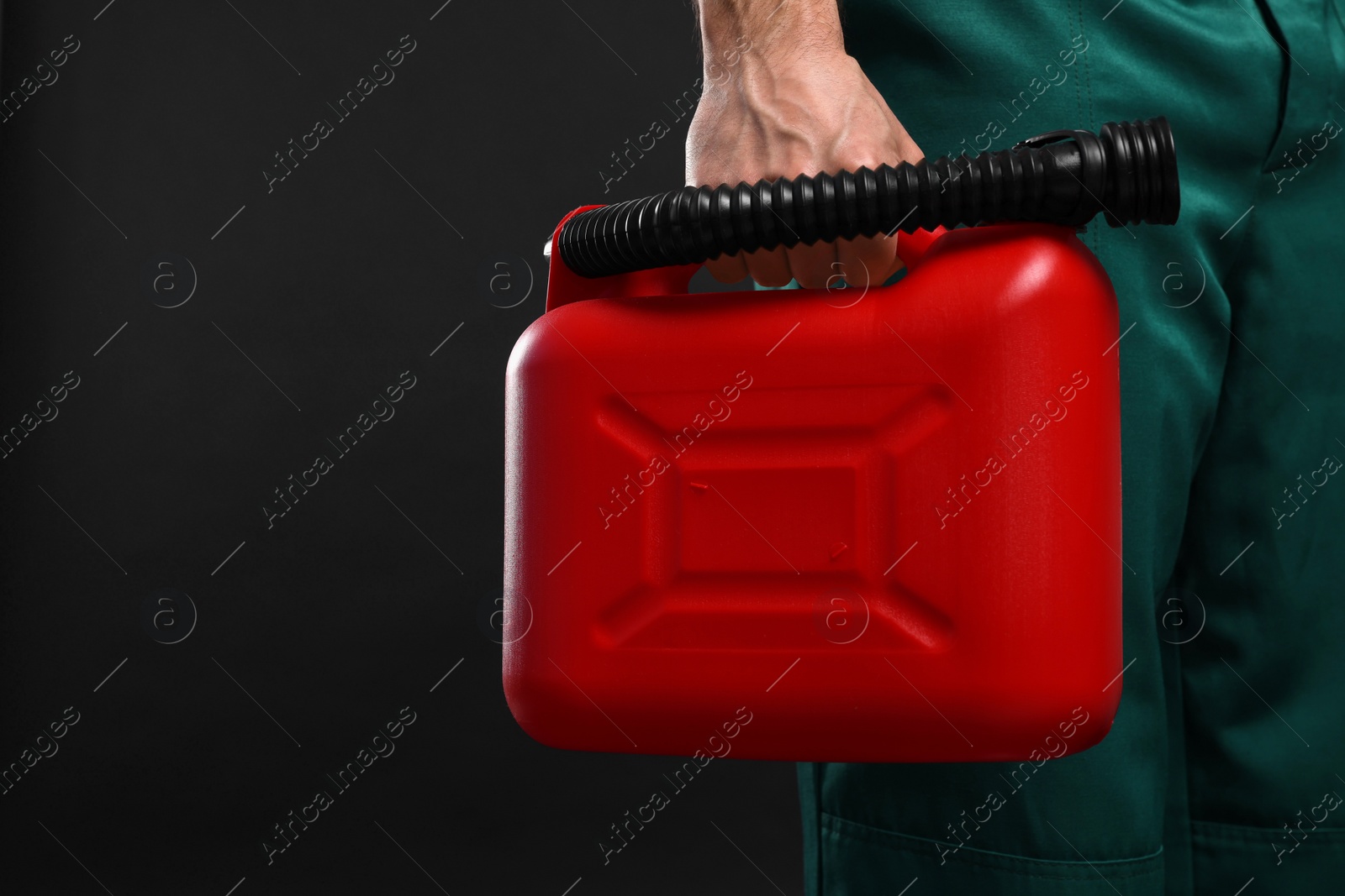 Photo of Man holding red canister on black background, closeup. Space for text