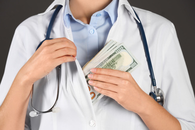 Photo of Doctor putting bribe into pocket on black background, closeup. Corruption in medicine