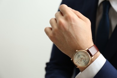 Photo of Businessman with luxury wrist watch on light grey background, closeup. Space for text