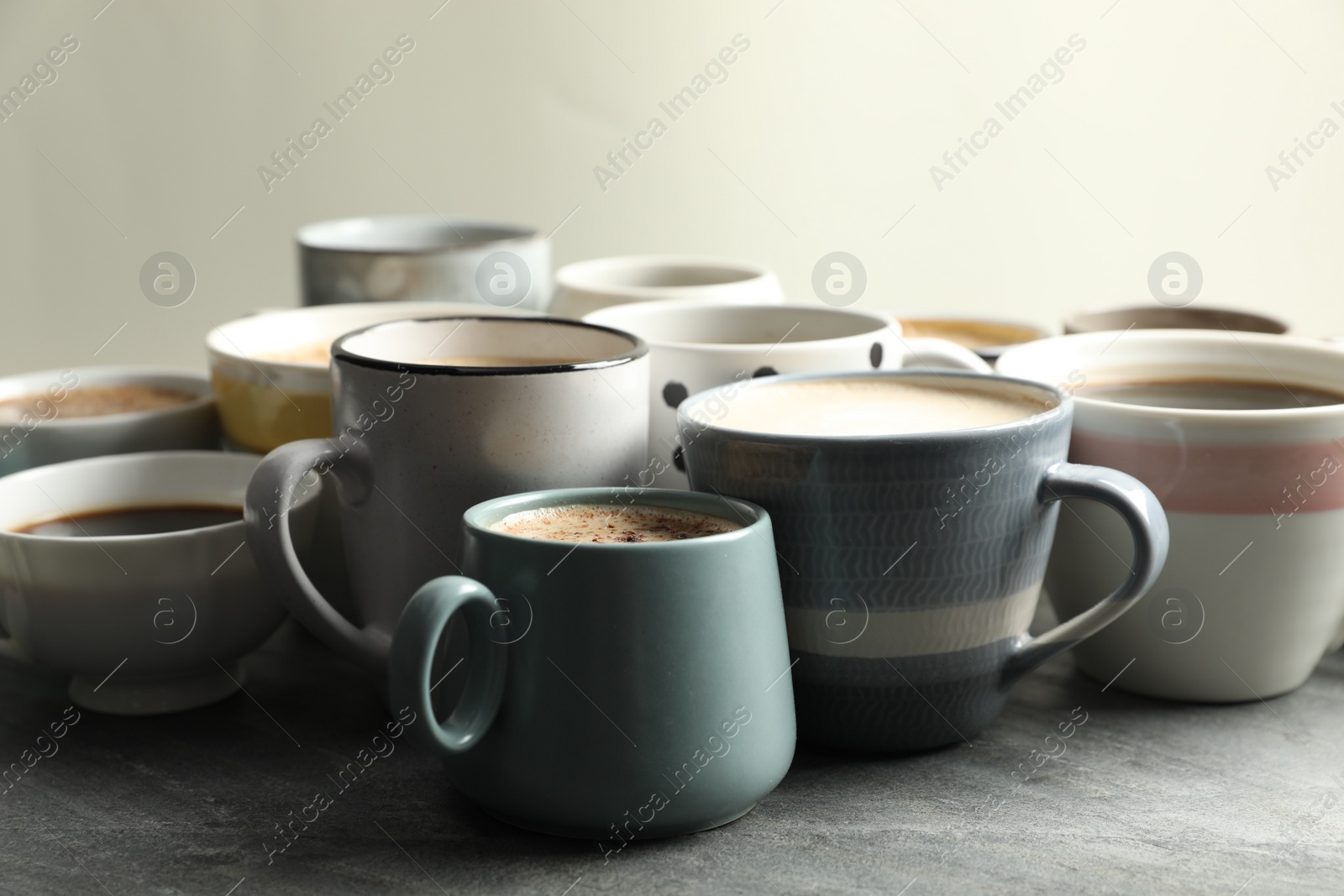 Photo of Many cups of different coffees on slate table
