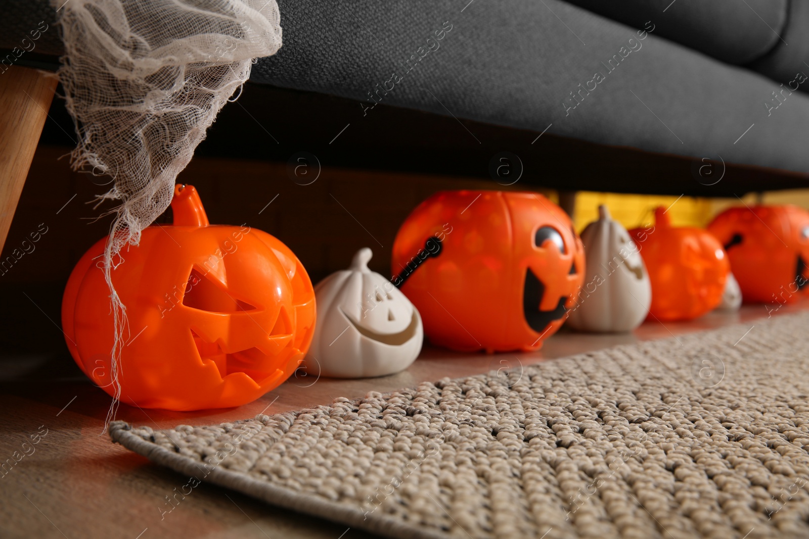 Photo of Different pumpkin shaped candle holders on floor in room