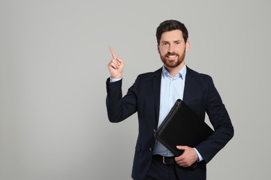 Handsome real estate agent with documents on grey background, space for text