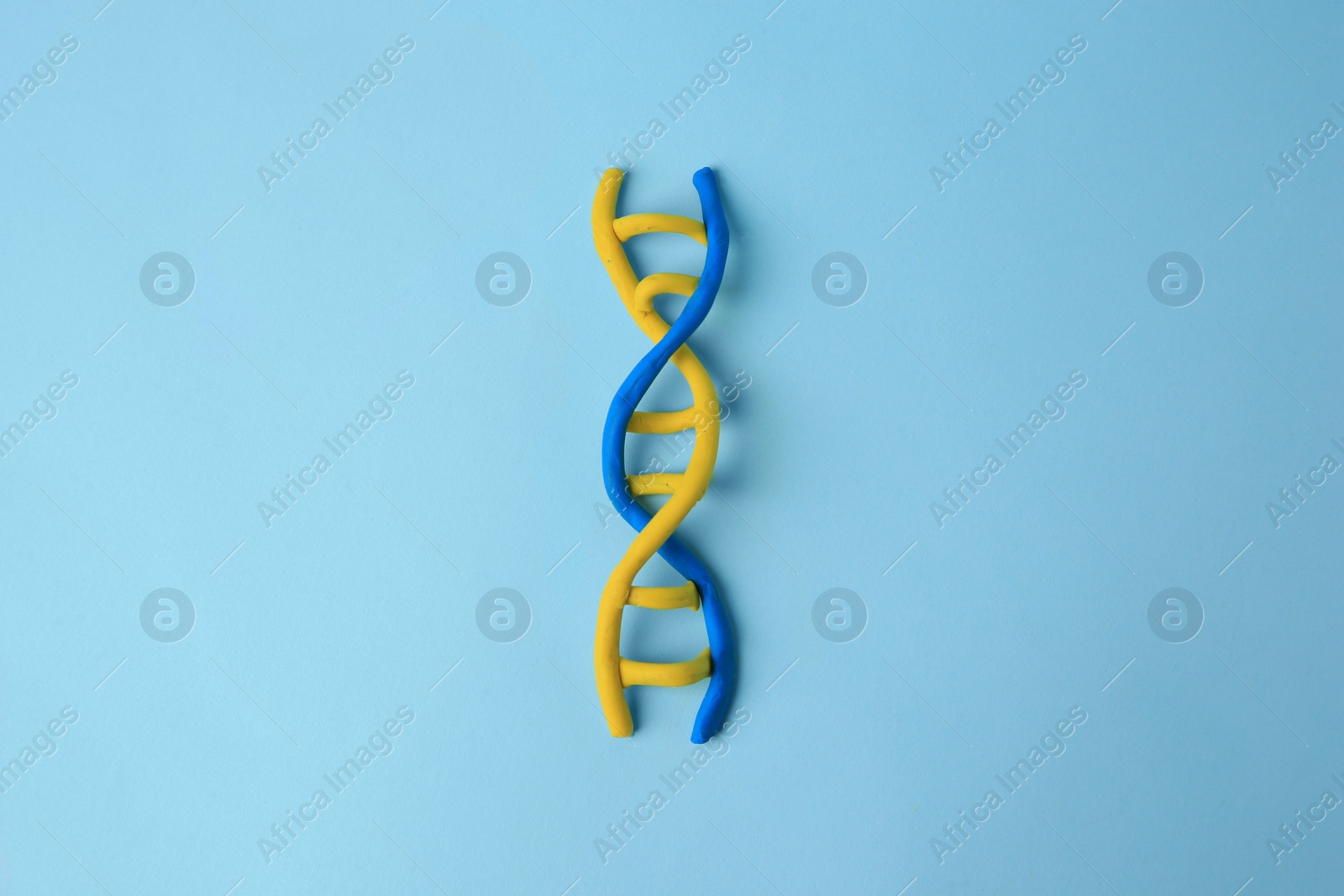 Photo of DNA molecule model made of colorful plasticine on light blue background, top view