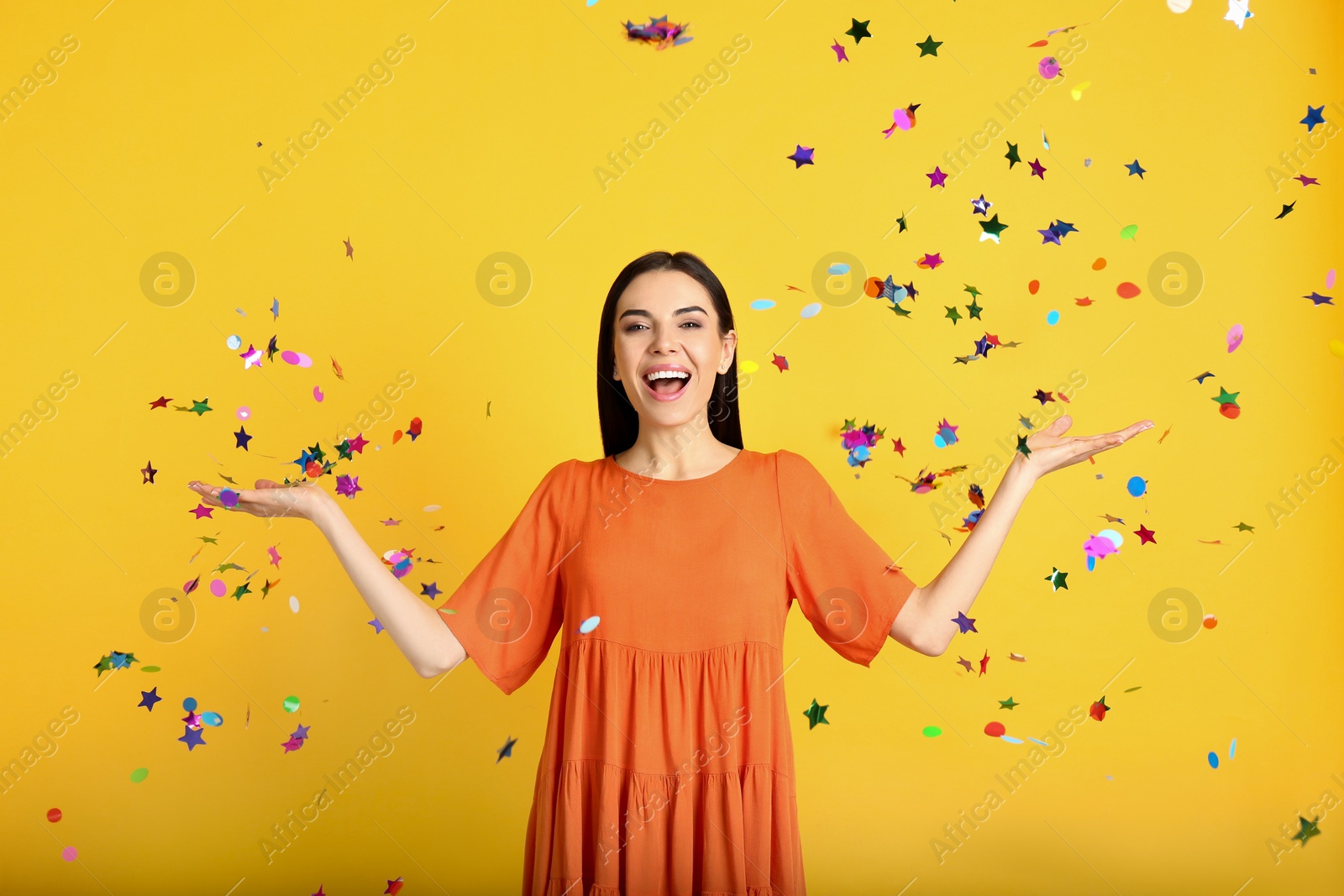 Photo of Emotional woman and falling confetti on yellow background