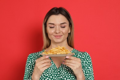 Photo of Young woman with French fries on red background