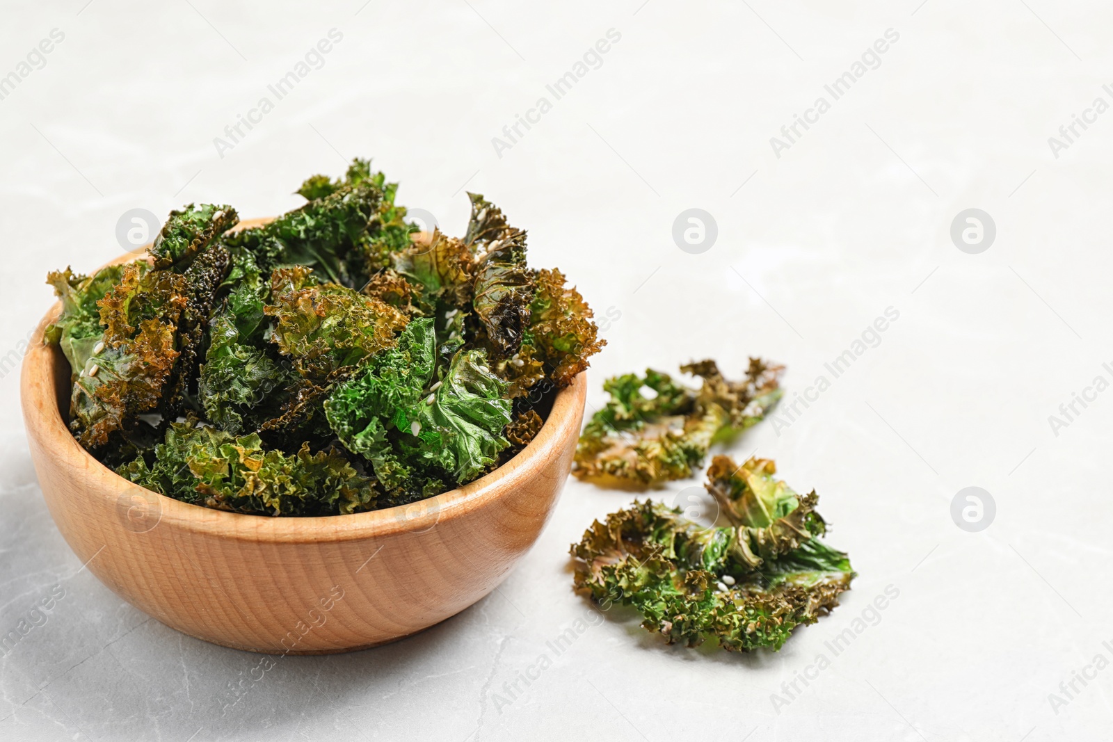 Photo of Tasty baked kale chips on grey marble table