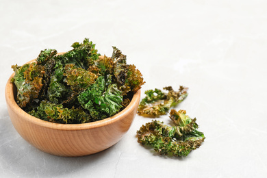 Photo of Tasty baked kale chips on grey marble table