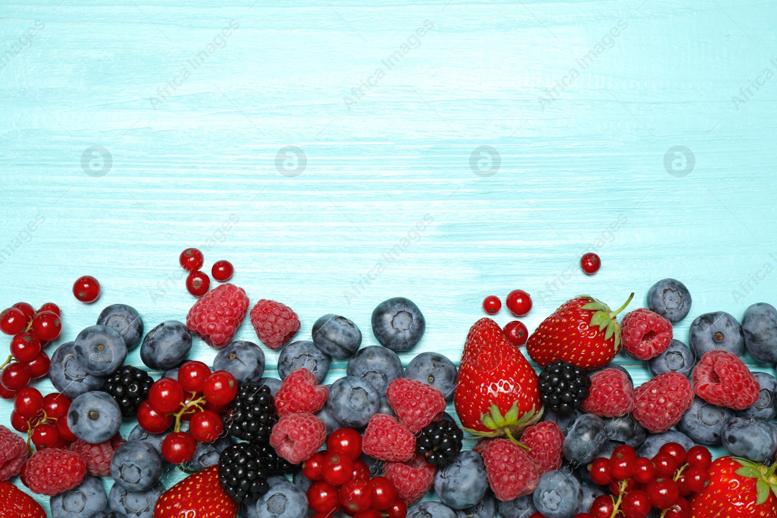 Photo of Different fresh berries on light blue table, flat lay. Space for text