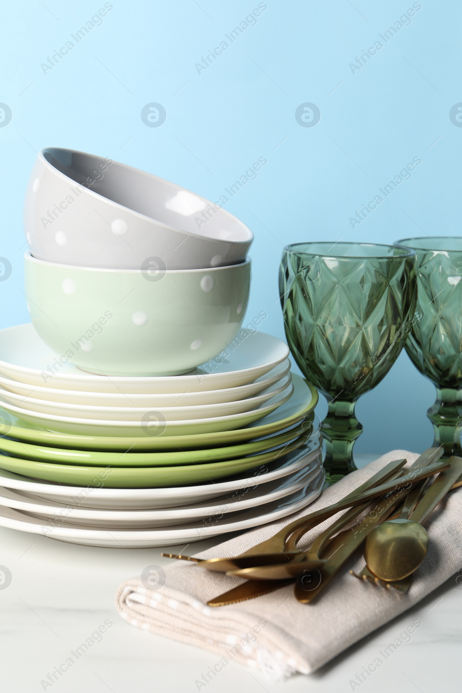 Photo of Beautiful ceramic dishware, glasses and cutlery on white marble table