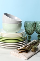 Photo of Beautiful ceramic dishware, glasses and cutlery on white marble table