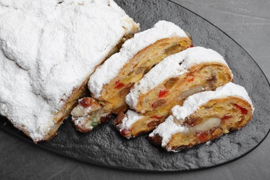 Photo of Traditional Christmas Stollen with icing sugar on black table, top view