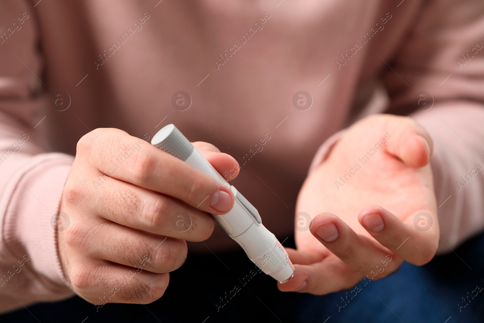 Photo of Diabetes test. Man checking blood sugar level with lancet pen, closeup