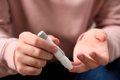 Photo of Diabetes test. Man checking blood sugar level with lancet pen, closeup