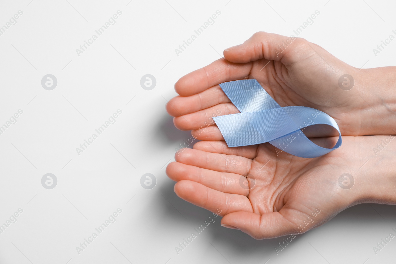 Photo of International Psoriasis Day. Woman with light blue ribbon as symbol of support on white background, top view. Space for text