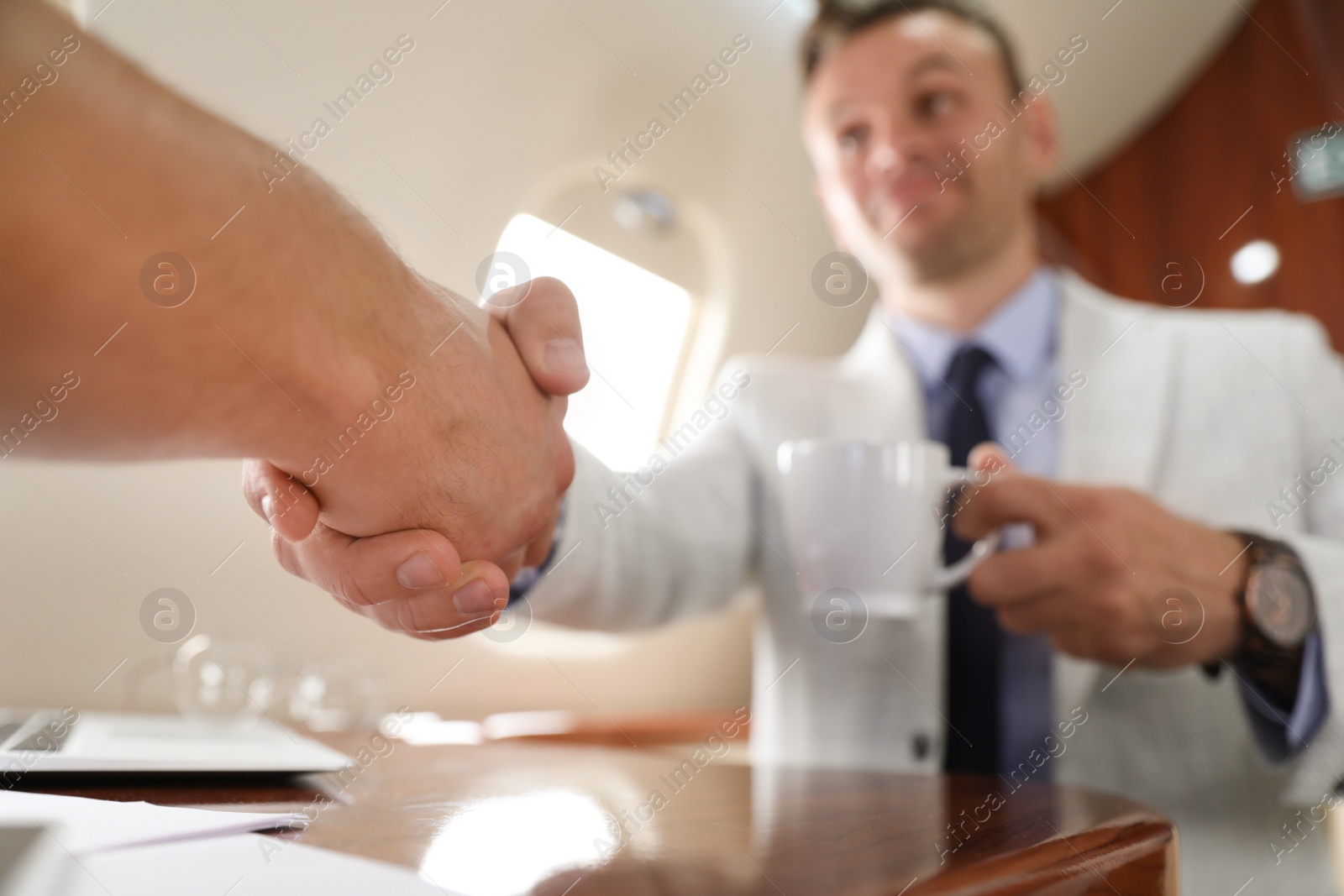 Photo of Young people shaking hands after bargaining on plane, closeup. Business deal