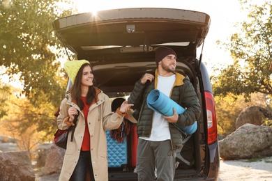 Photo of Young couple with camping equipment near car trunk outdoors