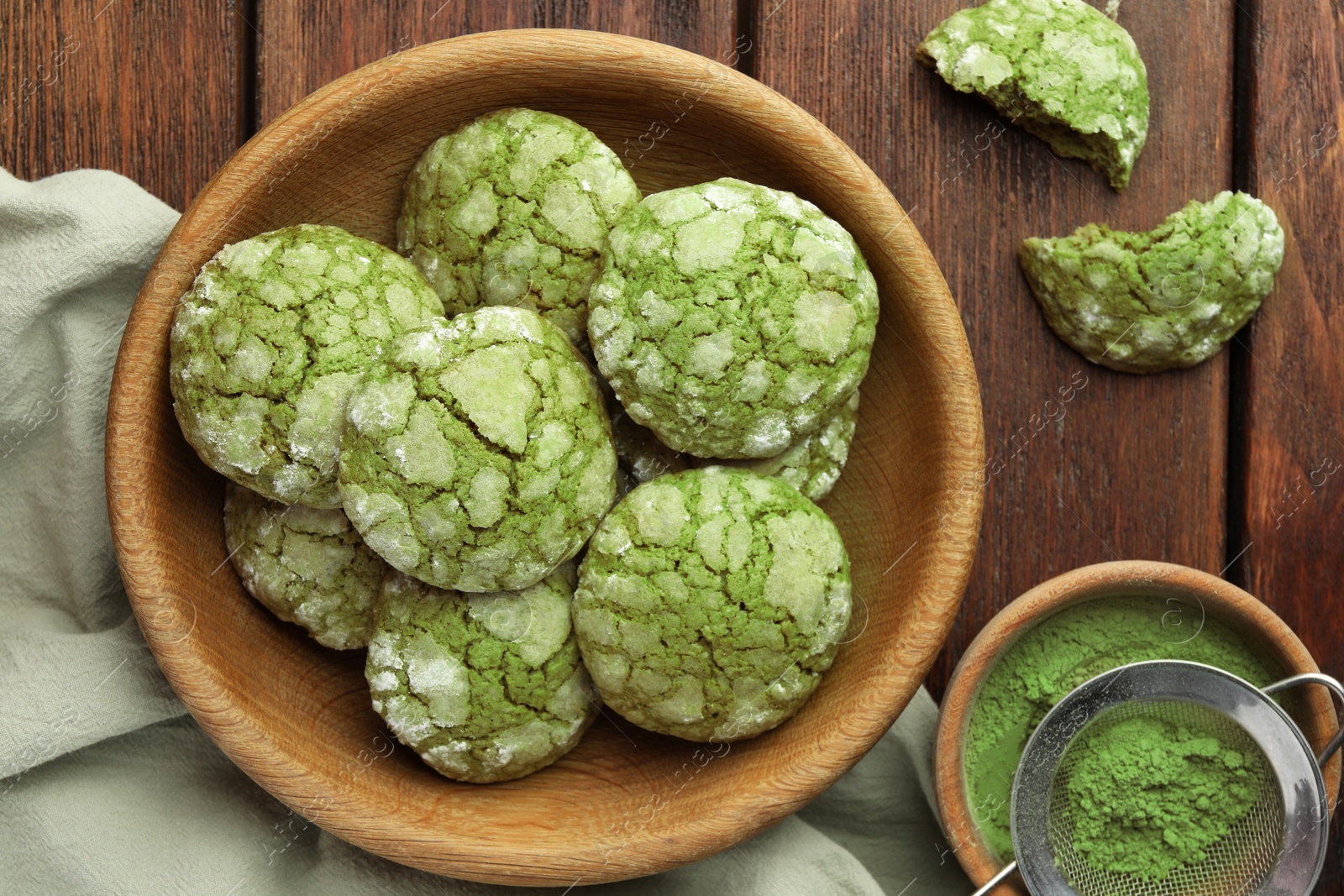 Photo of Bowl with tasty matcha cookies and powder on wooden table, flat lay