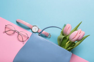 Photo of Flat lay composition with stylish woman's handbag and spring flowers on color background