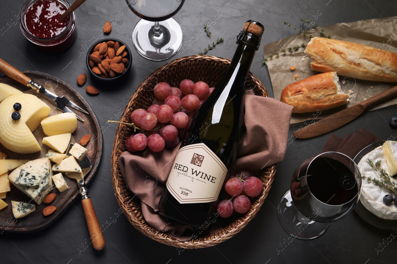 Photo of Flat lay composition with bottle of red wine and snacks on black table