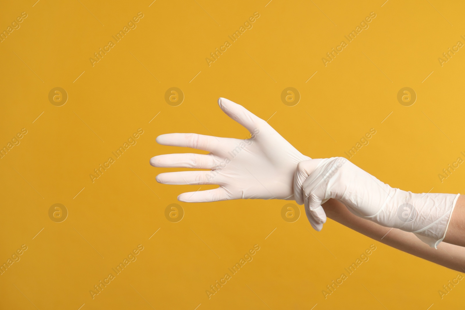 Photo of Doctor wearing medical gloves on yellow background, closeup