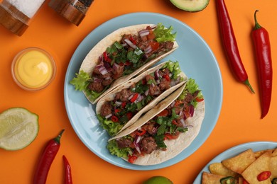 Photo of Flat lay composition with delicious tacos on orange table