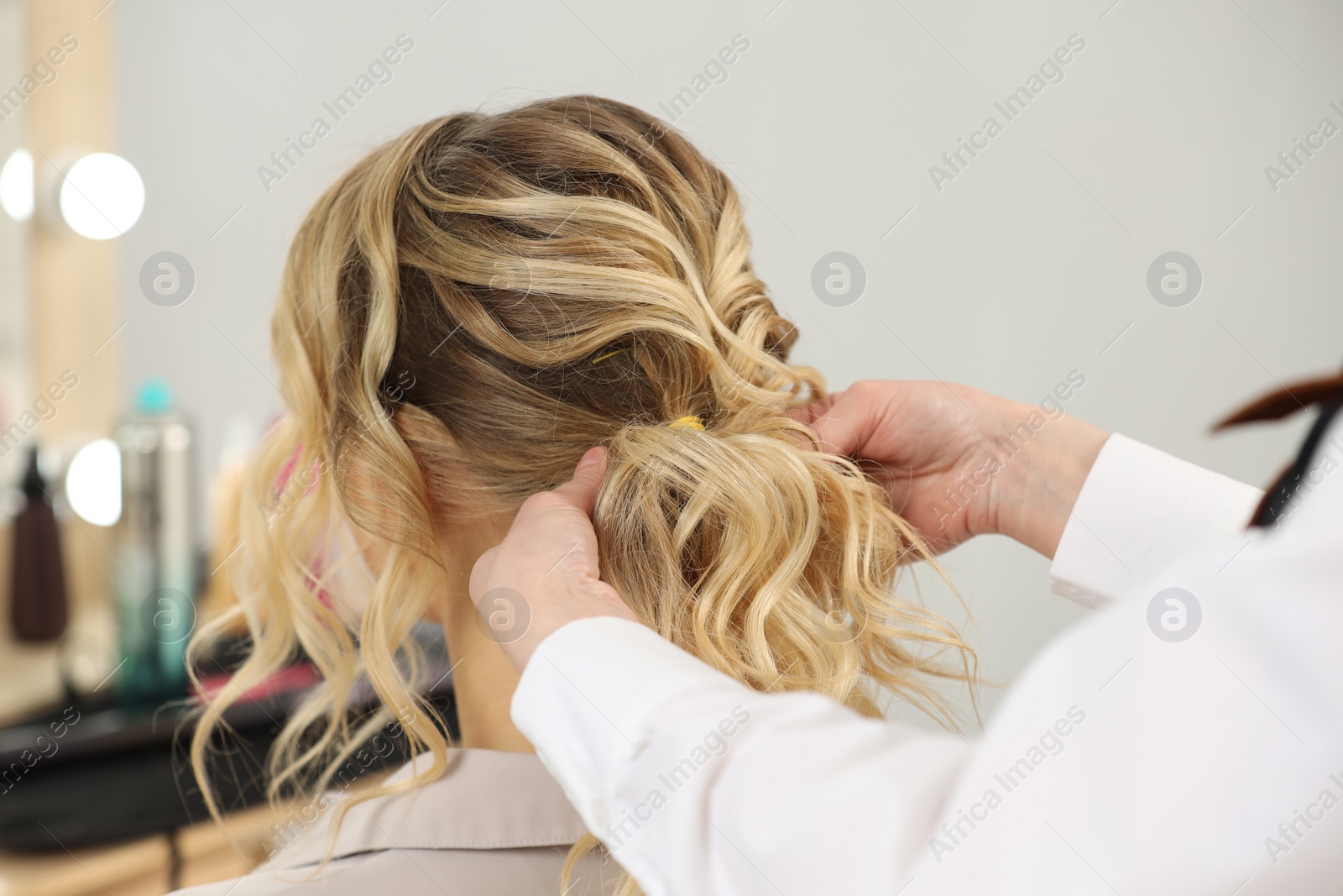 Photo of Hair styling. Professional hairdresser working with client indoors, closeup