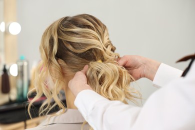 Photo of Hair styling. Professional hairdresser working with client indoors, closeup