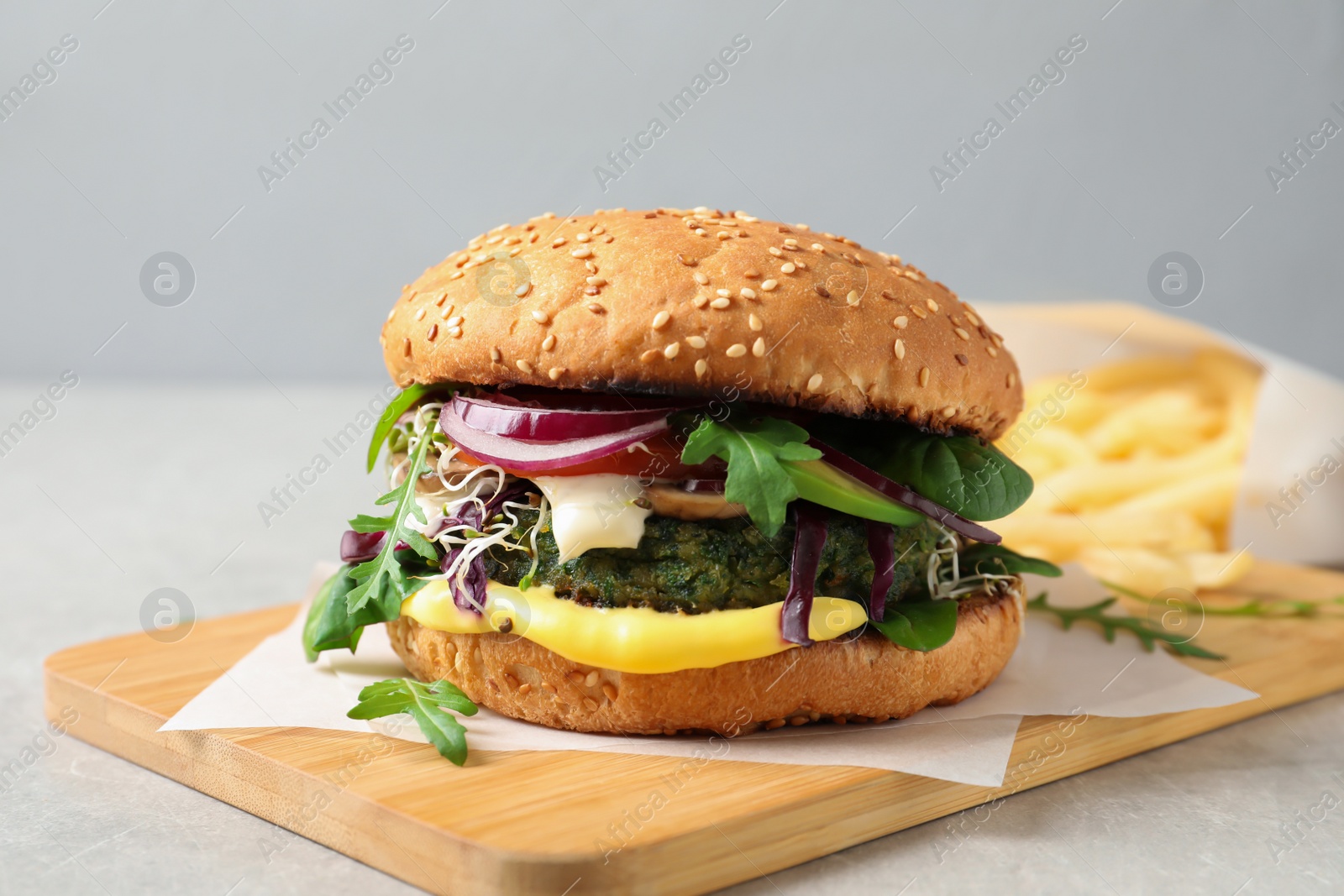 Photo of Board with tasty vegetarian burger on table