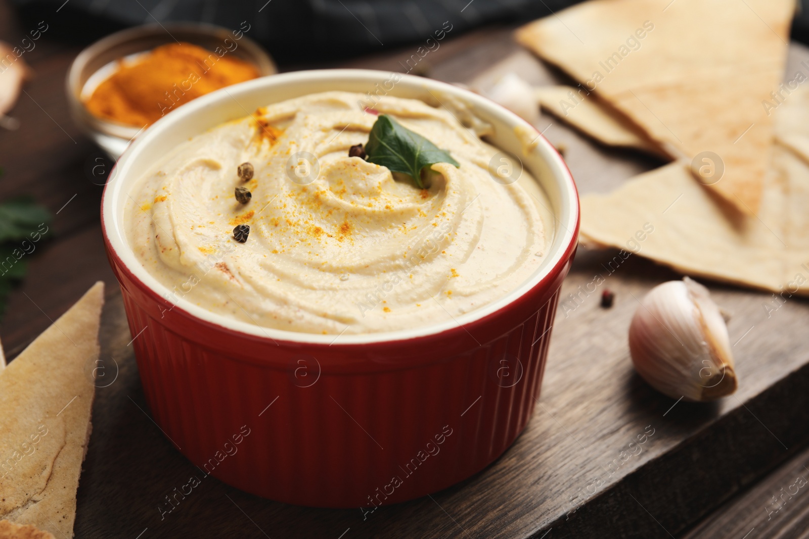 Photo of Delicious hummus with pita chips on wooden table, closeup